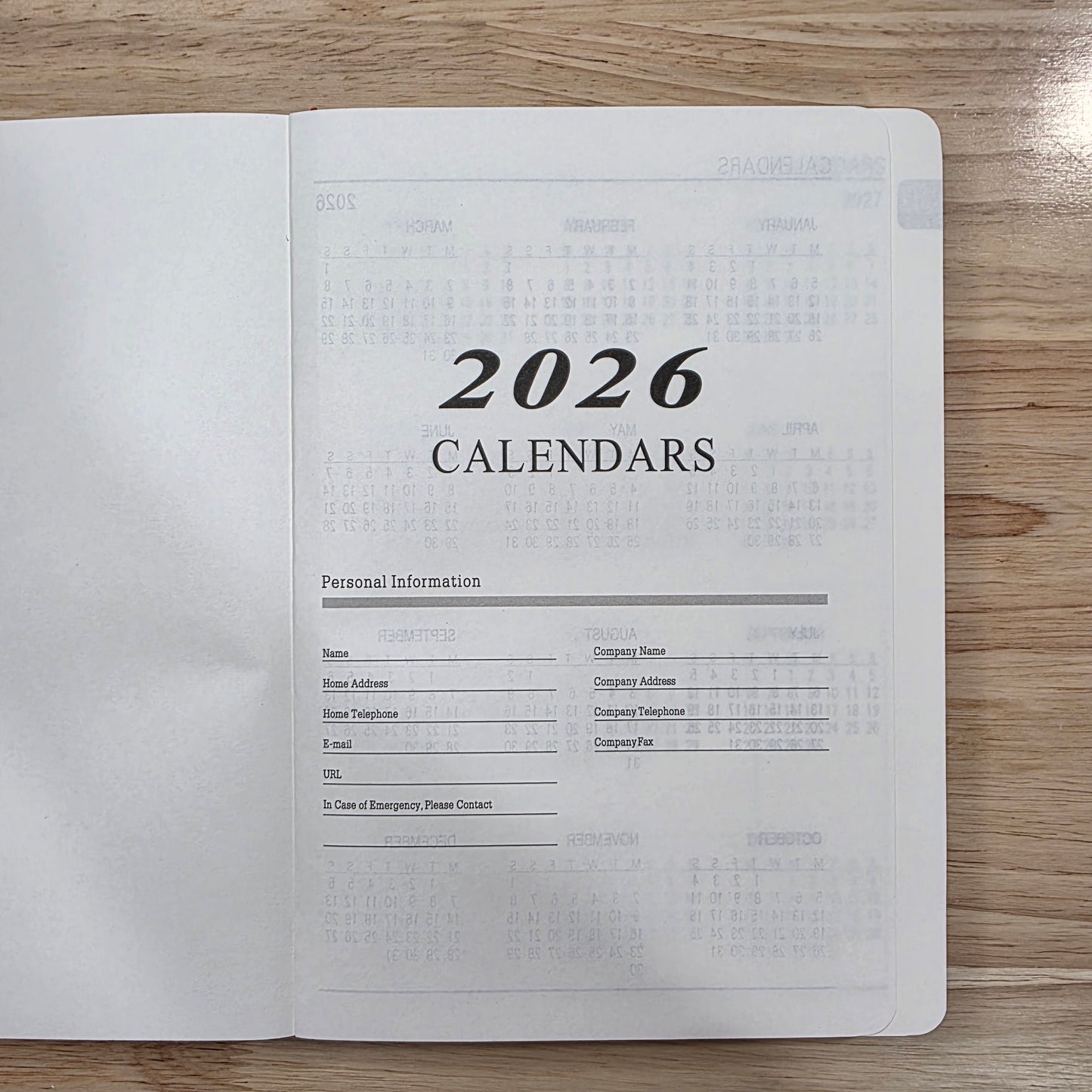 Flat lay of the front page of planner that reads "2026 Calenders", on a wooden surface