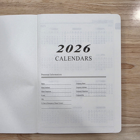 Flat lay of the front page of planner that reads "2026 Calenders", on a wooden surface