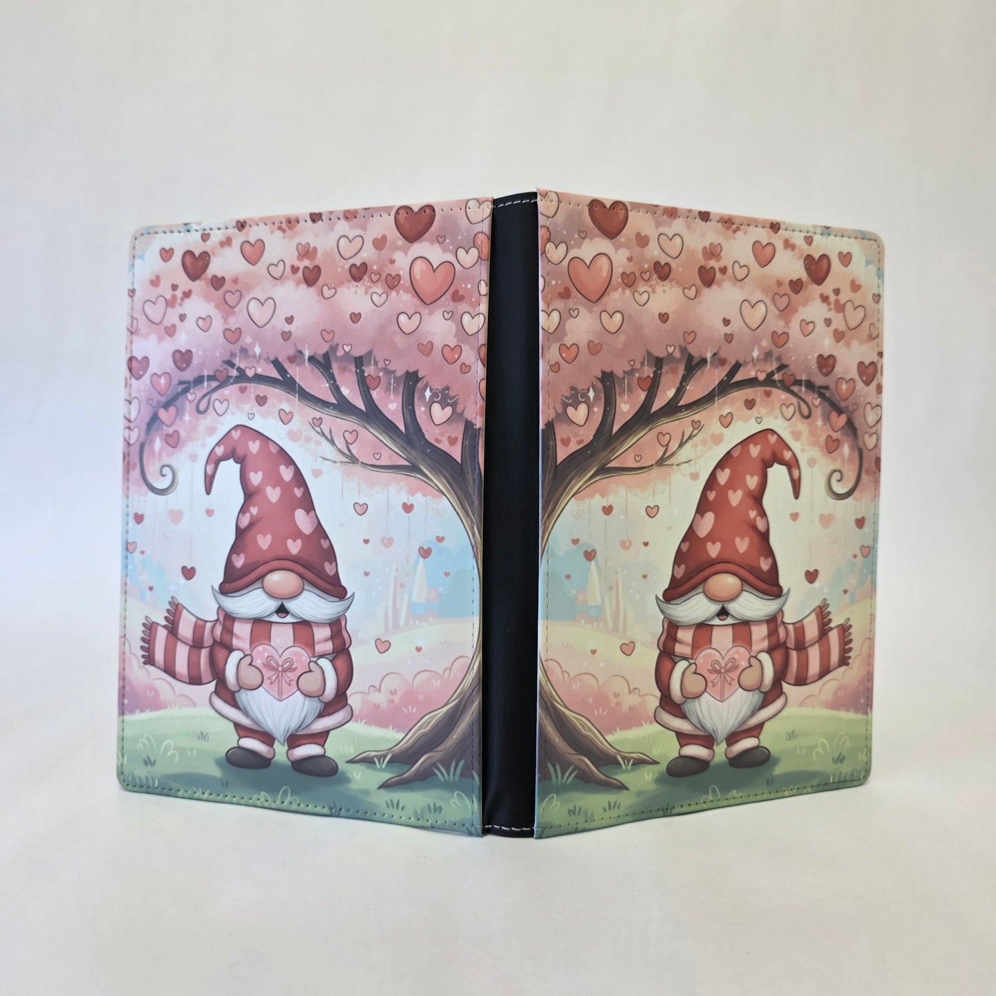 Journal cover with Gnome heart-themed design. A gnome standing beneath a pink tree. Pink and red hearts. 