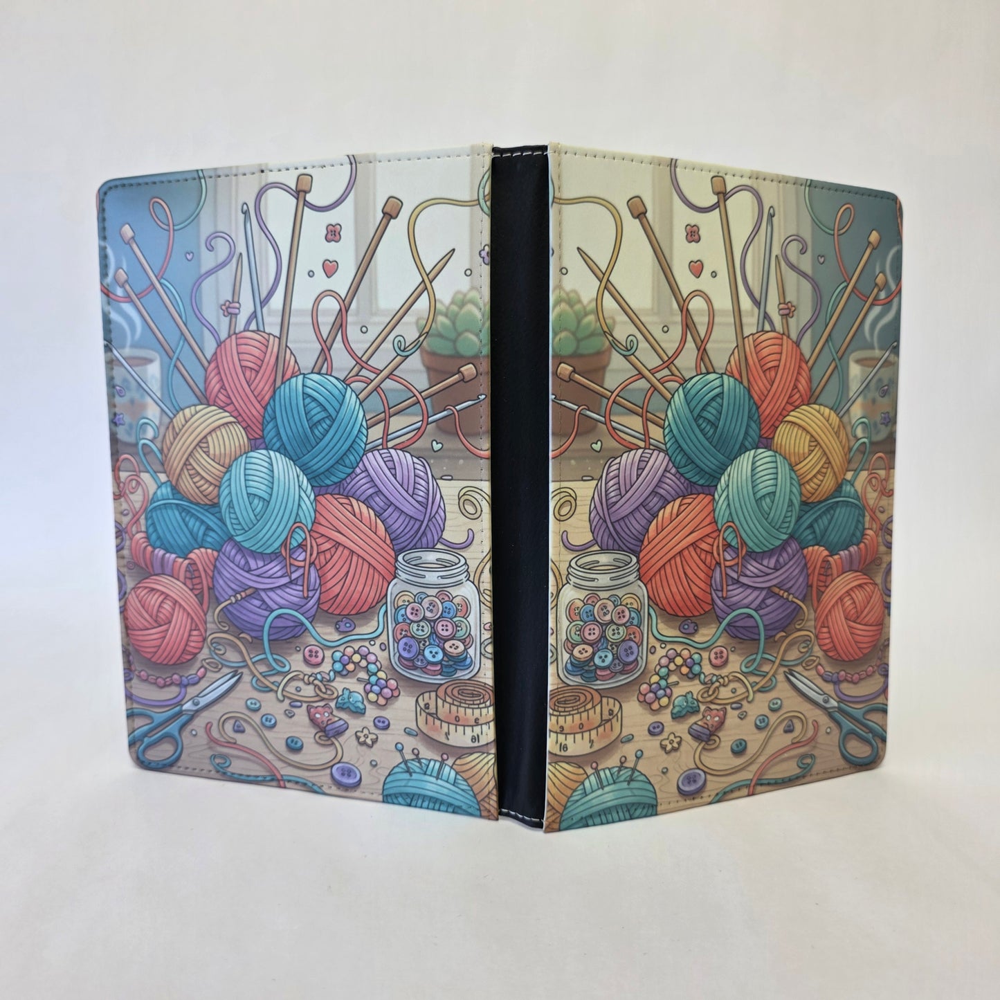 Notebook cover with colorful yarn balls and knitting tools.