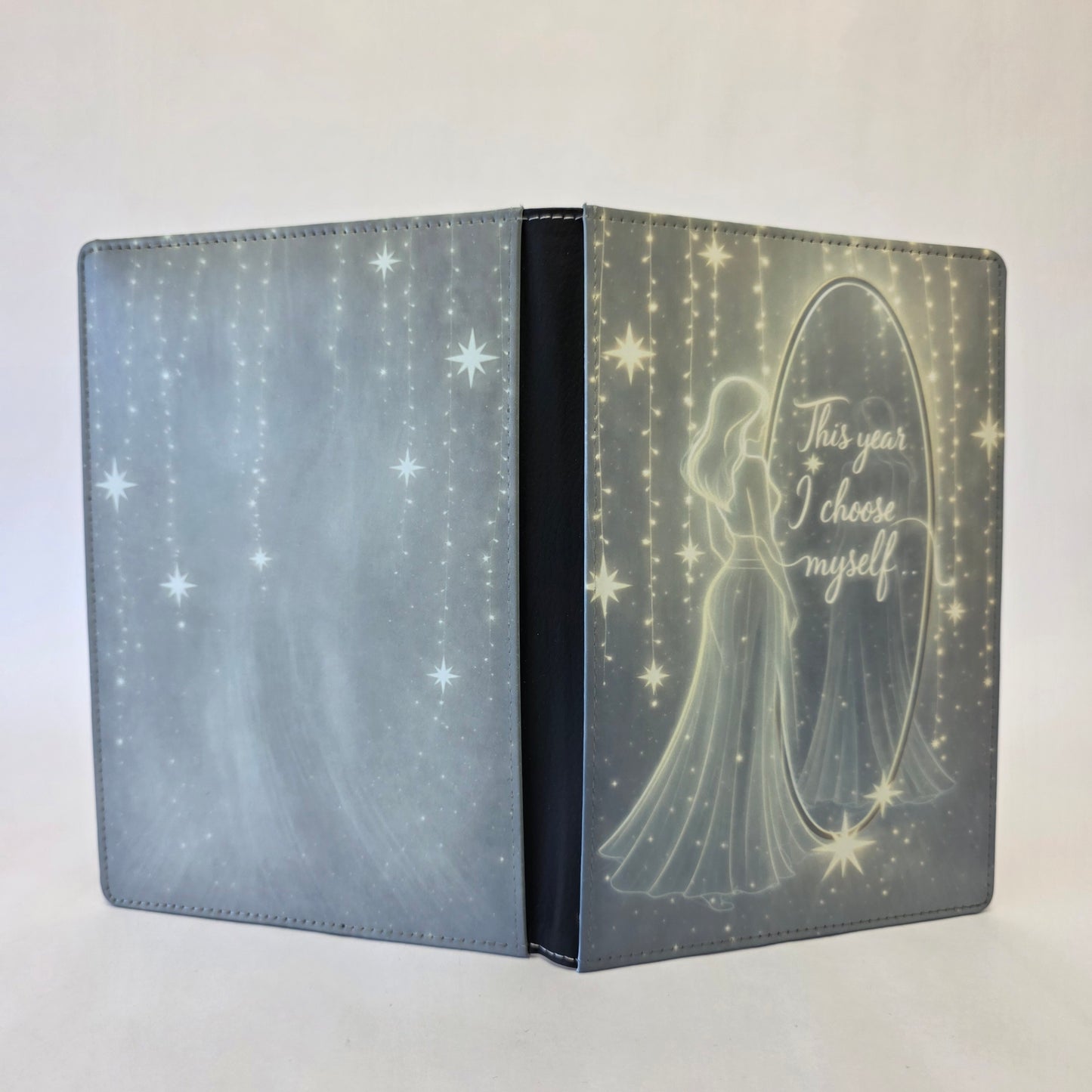 Journal cover with a silhouette of a woman looking into a mirror and 'This year I choose myself' text on the mirror. Yellow and gray tones, with a slight glow.