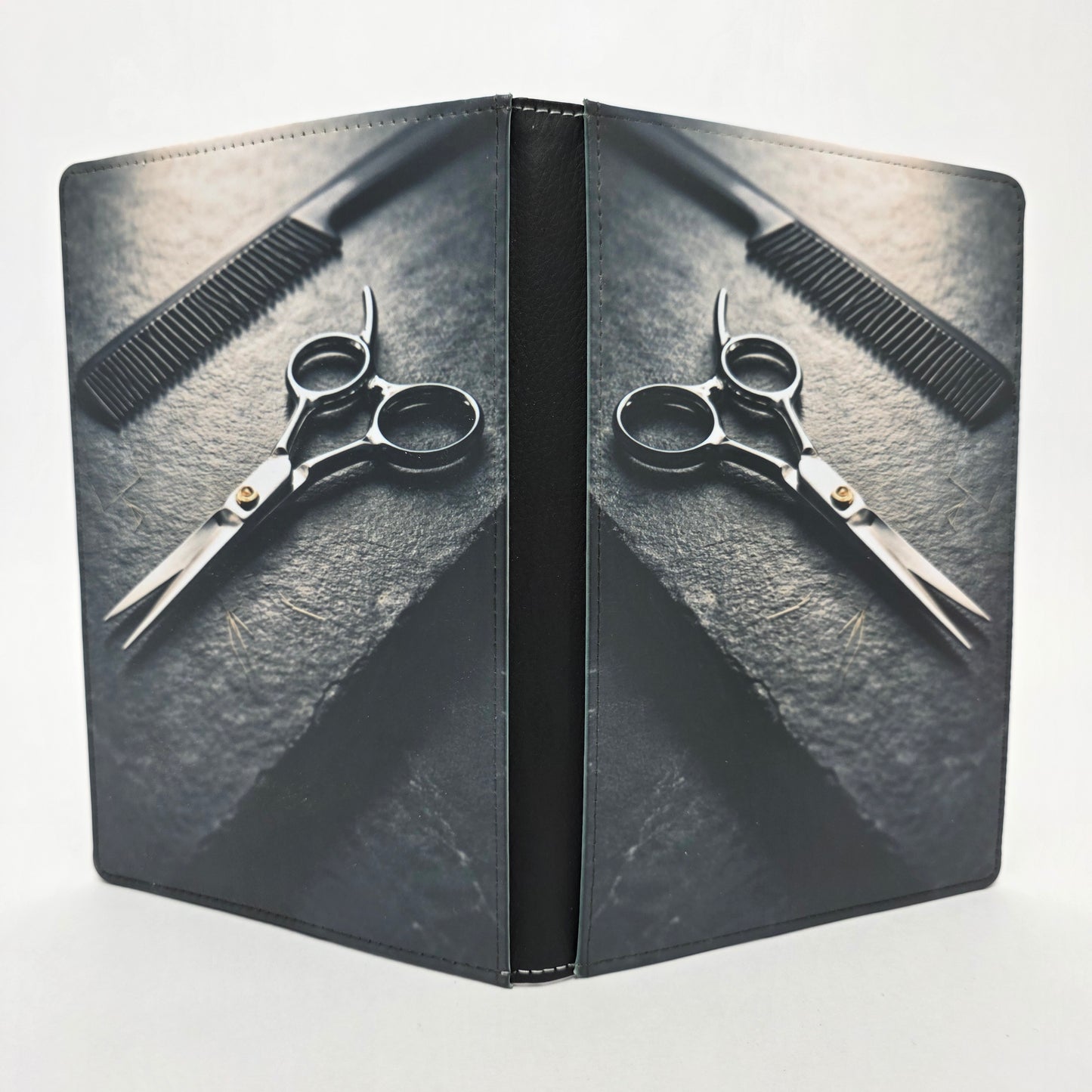 Scissors and comb on a textured slate surface. Grayscale color.