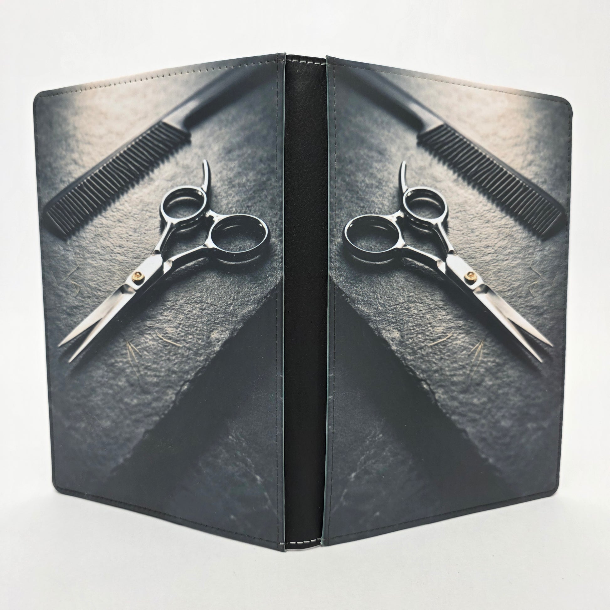 Scissors and comb on a textured slate surface. Grayscale color.