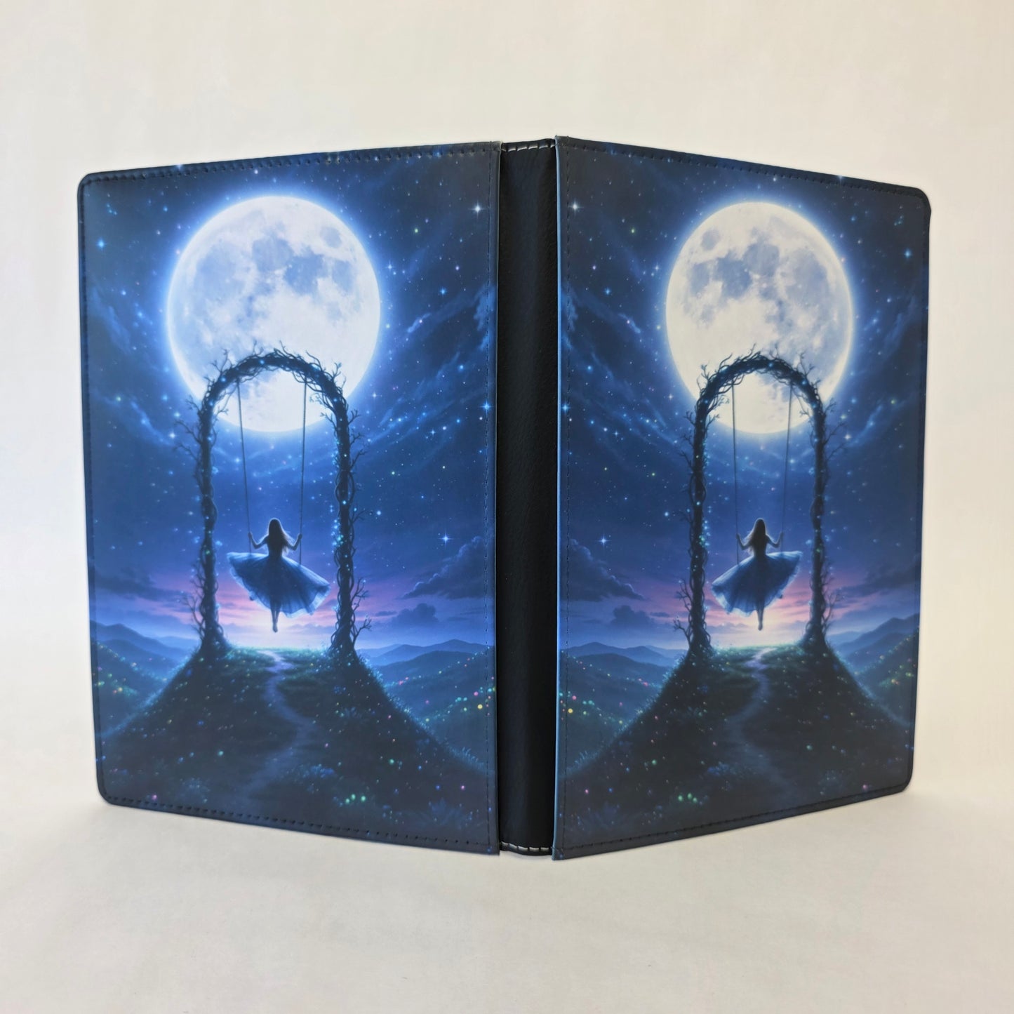 Notebook cover with a fantasy design of a woman on a swing under a large moon.
