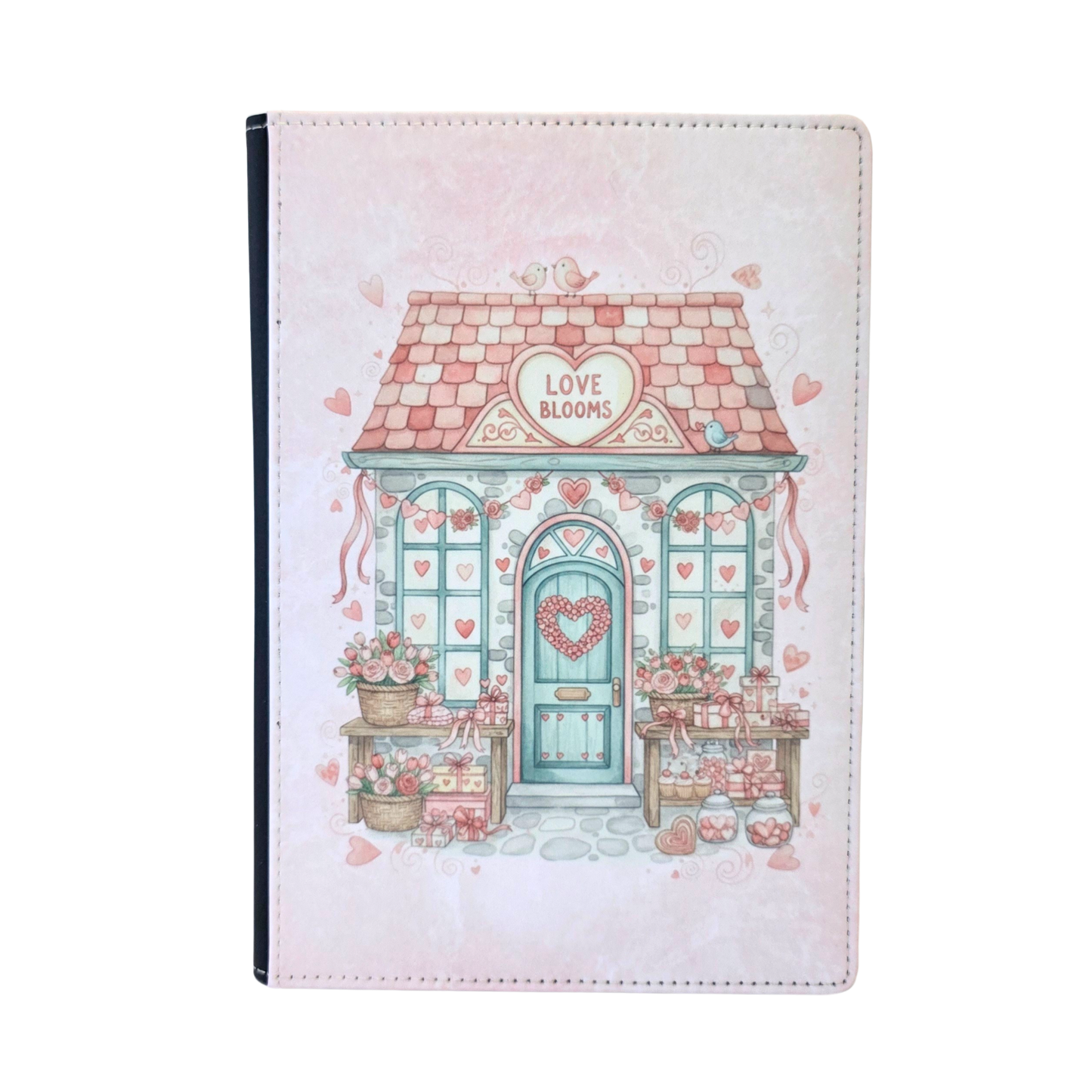 Notebook cover with a cute house illustration and 'Love Blooms' text on a heart sign above the door. Pink color theme.