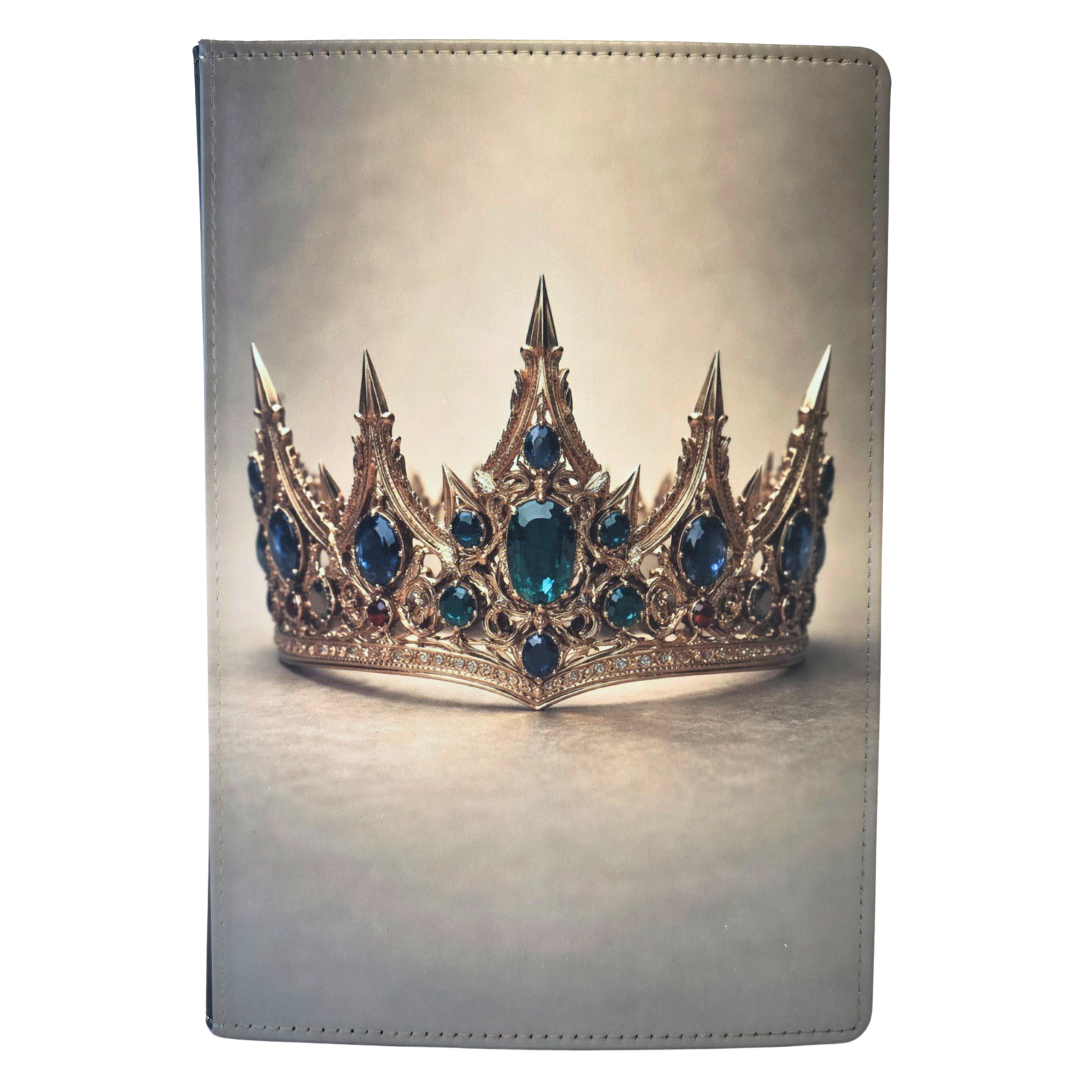A journal cover with a gold crown and emerald stones on a tan background.