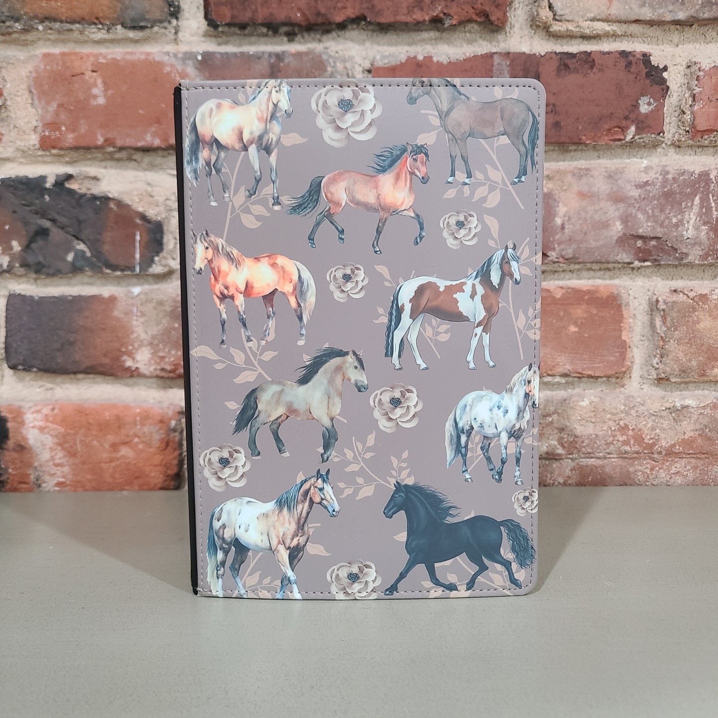 Decorative journal with a faux leather cover featuring a whimsical horse pattern on a gray background.