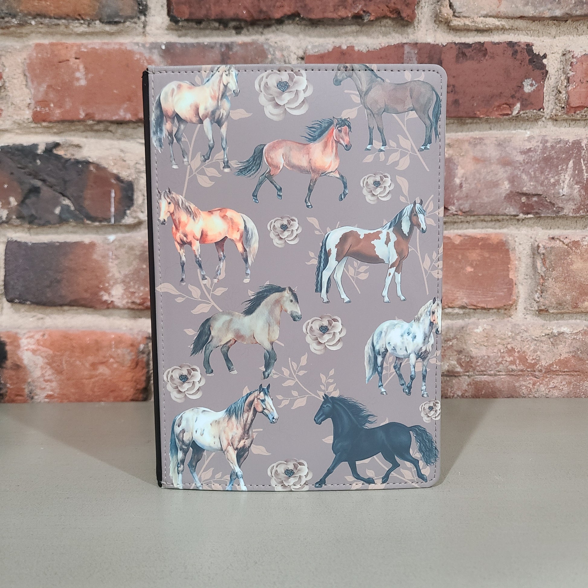 Decorative journal with a faux leather cover featuring a whimsical horse pattern on a gray background.